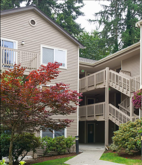 A building with a balcony and a tree with red leaves.