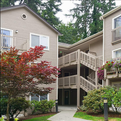 A building with a balcony and a tree with red leaves.