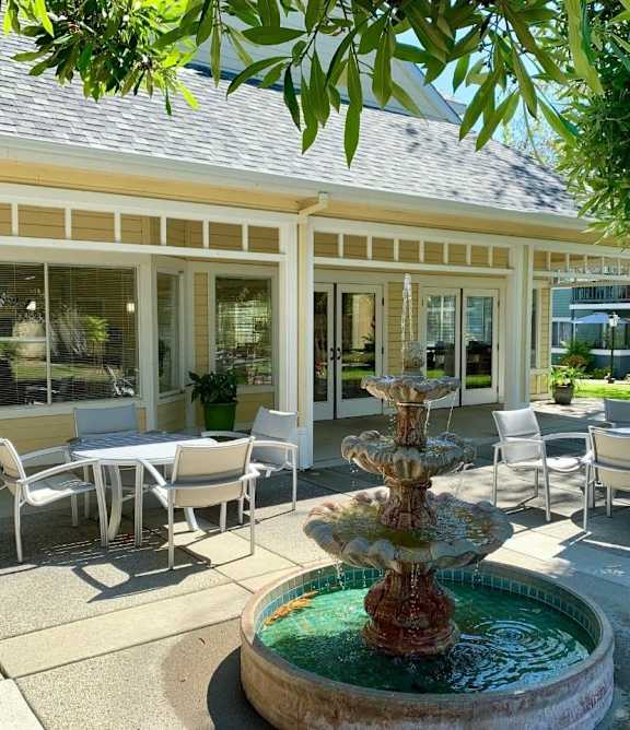 A fountain in the middle of a patio with chairs and a table.