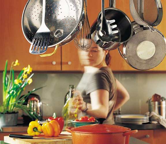 a woman in a kitchen with pots and pans over a stove at Overland Gardens, Landover