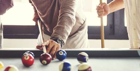 A person is playing pool with a cue in hand.