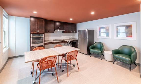 a dining room with a table and chairs and a kitchen with a refrigerator