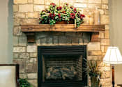 Thumbnail 9 of 11 - A stone fireplace with a wooden mantle and a plant on top.