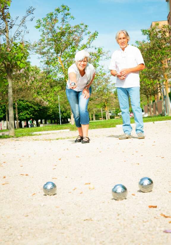 Two people playing with silver balls in a park.