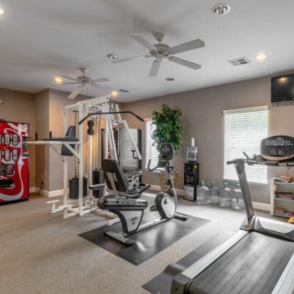 the retreat apartments l gym with cardio equipment and a coke machine