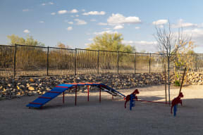two children playing on a blue swing set in a playground