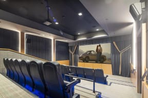 a view of a screening room with blue chairs and a movie screen on the wall