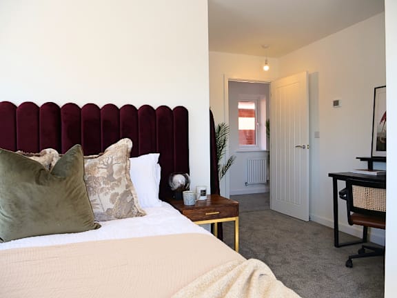 a nightstand with a lamp and a jar on it next to a bed