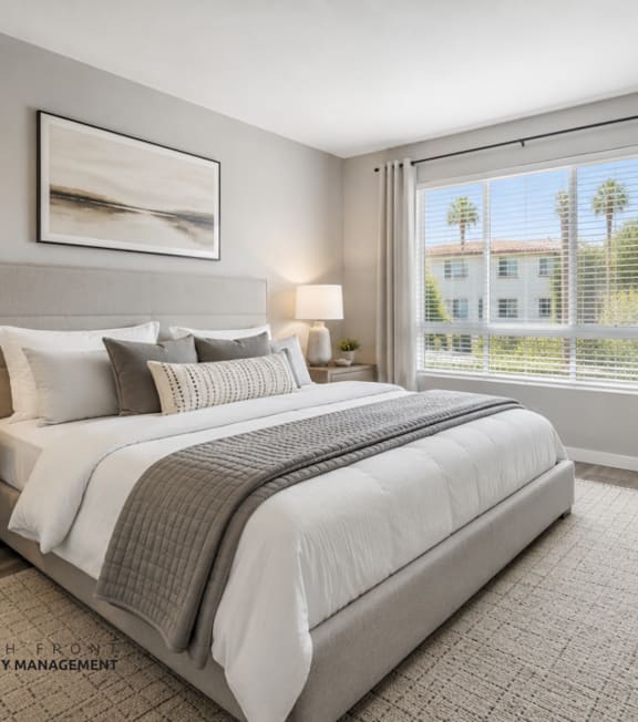 A well-lit bedroom with a large bed, two lamps, and a framed picture on the wall.