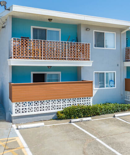 a blue and white apartment building with a parking lot in front of it
