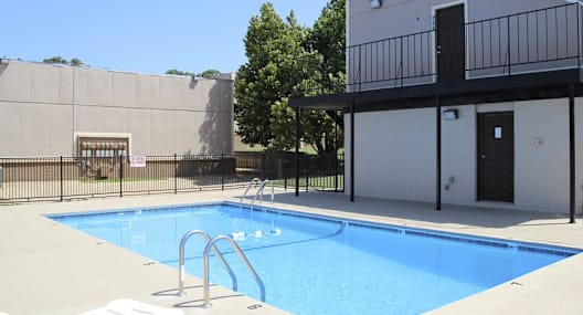 a swimming pool in front of a building with chairs