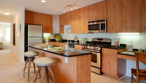a kitchen with wooden cabinets and a counter with three stools  at Spa Cove Apartments, Annapolis, 21403