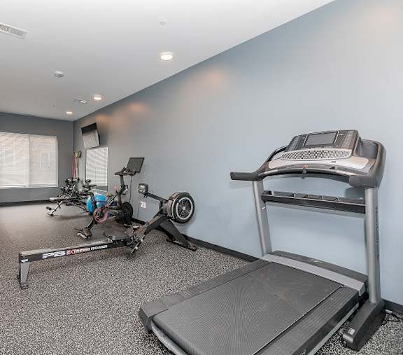 A home gym with a treadmill, rowing machine, and weights.at The Lumos Apartments in Cleveland, OH