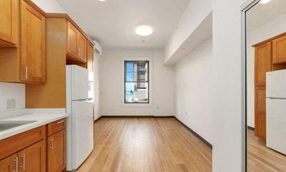 an empty kitchen with a refrigerator and a window