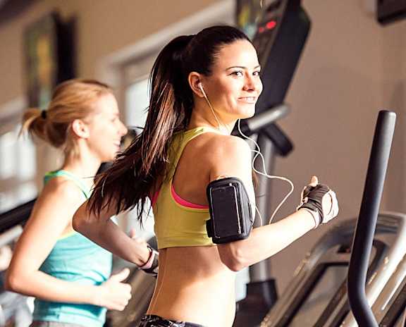two women running on a treadmill at the gym