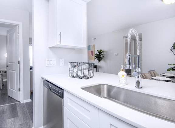 a kitchen with a sink and a dishwasher and a door to a living room