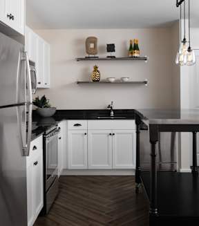 a kitchen with white cabinets and a black counter top
