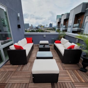 a terrace with a wooden floor and white couches with red and white pillows