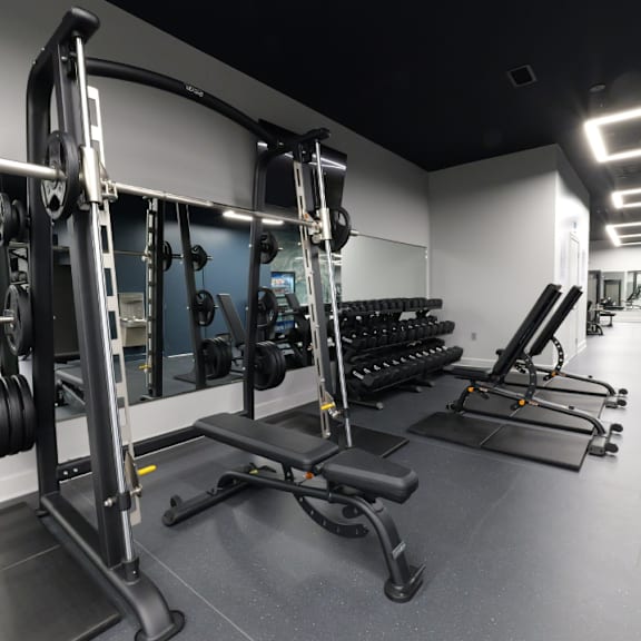A gym with a variety of equipment including weights and benches.