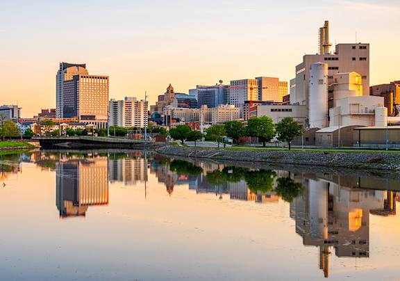 A city skyline is reflected in a body of water.