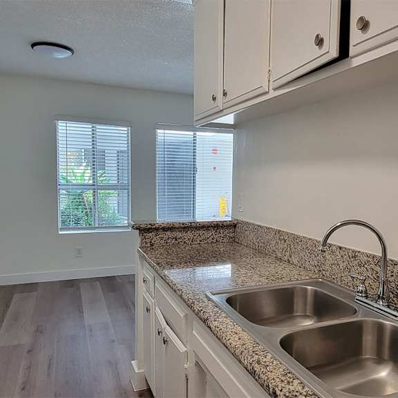A kitchen with granite countertops and stainless steel sinks.