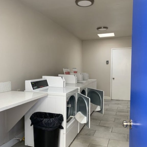 a row of washers and dryers in a room with a blue door