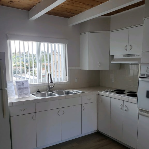 a kitchen with white cabinets and a window