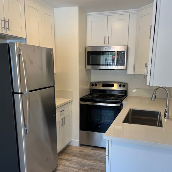 a kitchen with white cabinets and stainless steel appliances