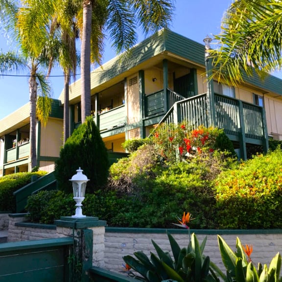 a large yellow and green apartment building with palm trees in front of it