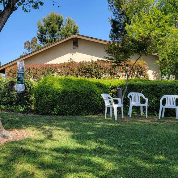 a group of lawn chairs sit in a grassy area in front of a house