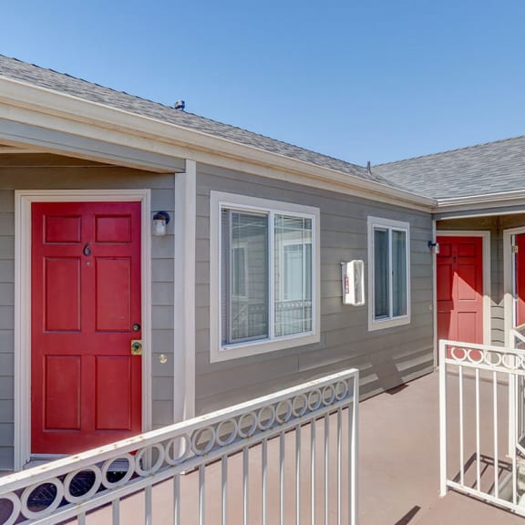a porch with a red door and a gray house with red doors