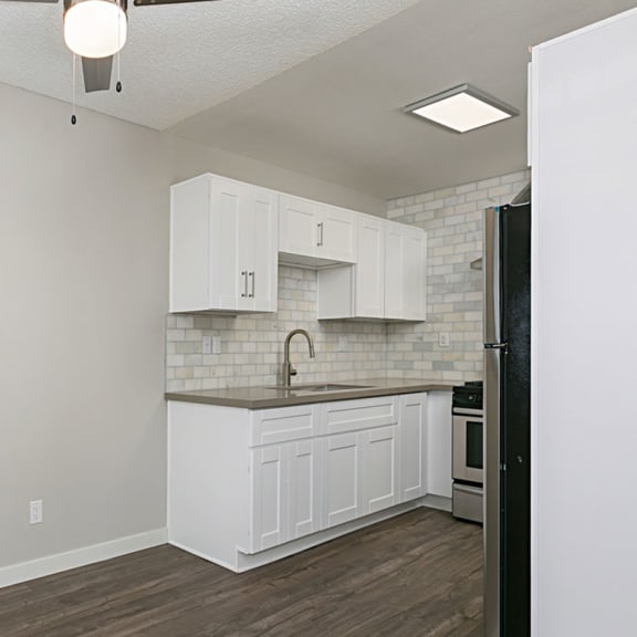 a kitchen with white cabinets and a black refrigerator