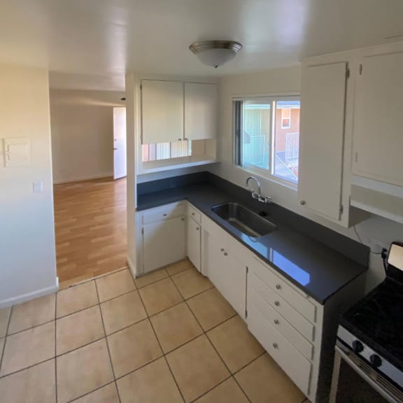 a kitchen with white cabinets and a black counter top