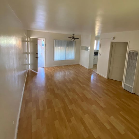 an empty living room with hardwood floors and a ceiling fan
