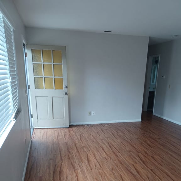 an empty room with a white door and wood floors