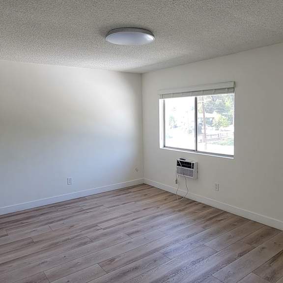 A room with a window and a wall-mounted air conditioner unit.