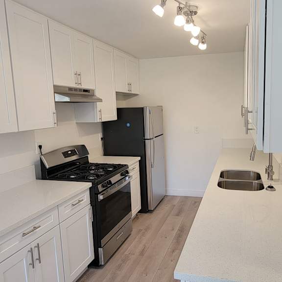 A kitchen with black appliances and white cabinets.