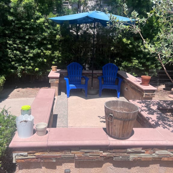 a patio with blue chairs and an umbrella