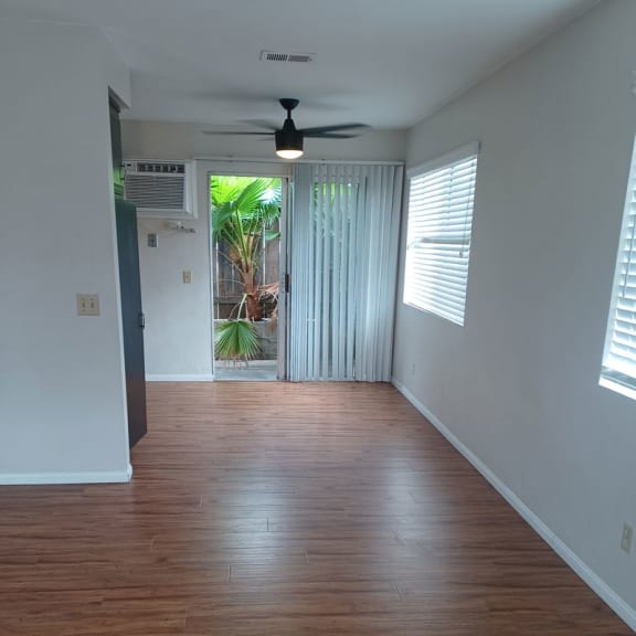 an empty room with wood floors and a ceiling fan