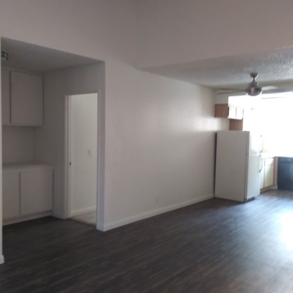 an empty living room with a refrigerator and cabinets