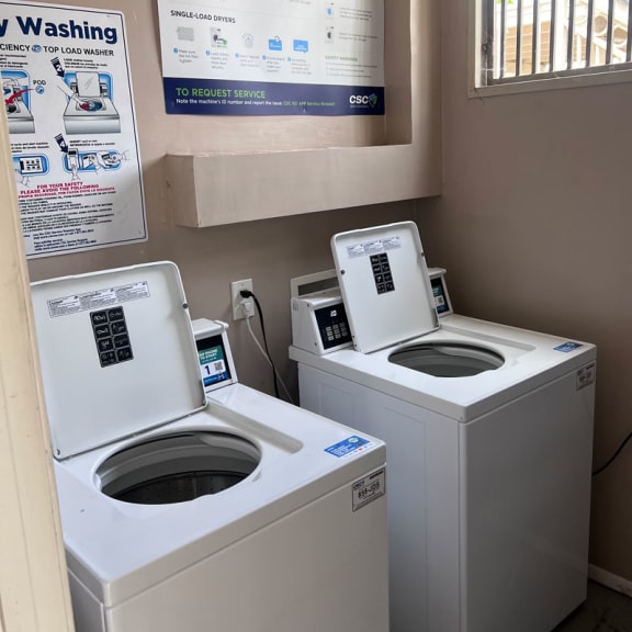 a laundry room with two washers and a dryer