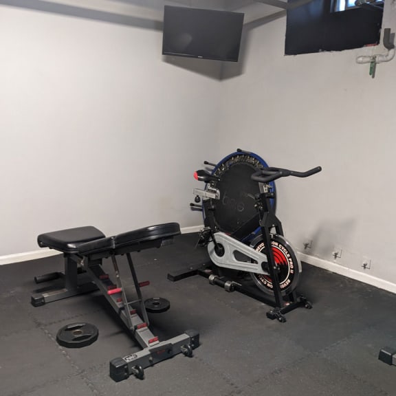 a home gym with a bike in the corner and a tv on the wall