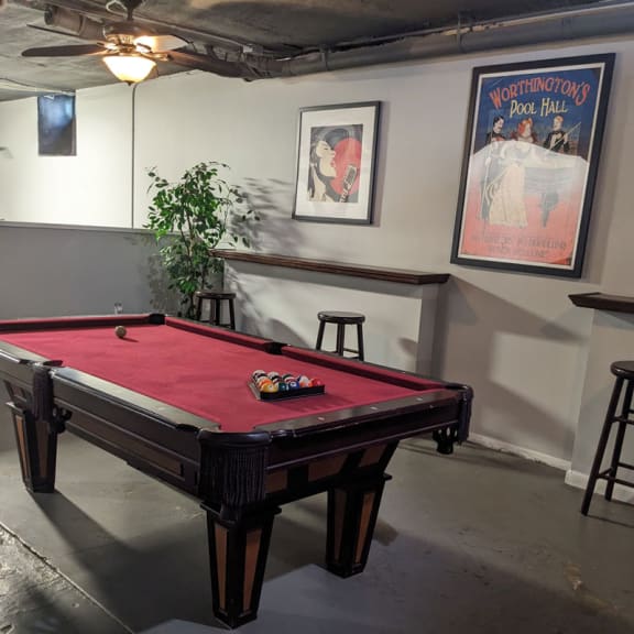 a red pool table in a room with a poster on the wall