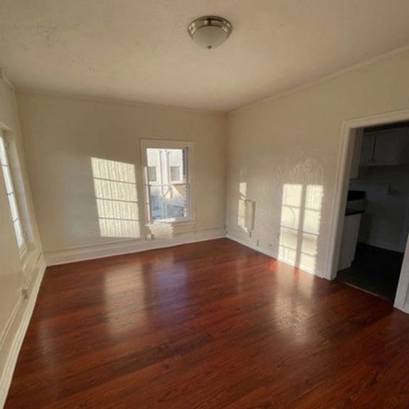 a bedroom with hardwood floors and a window