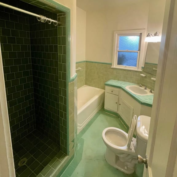 a bathroom with green tile and a white toilet