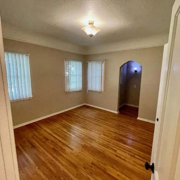 an empty room with a hardwood floor and three windows