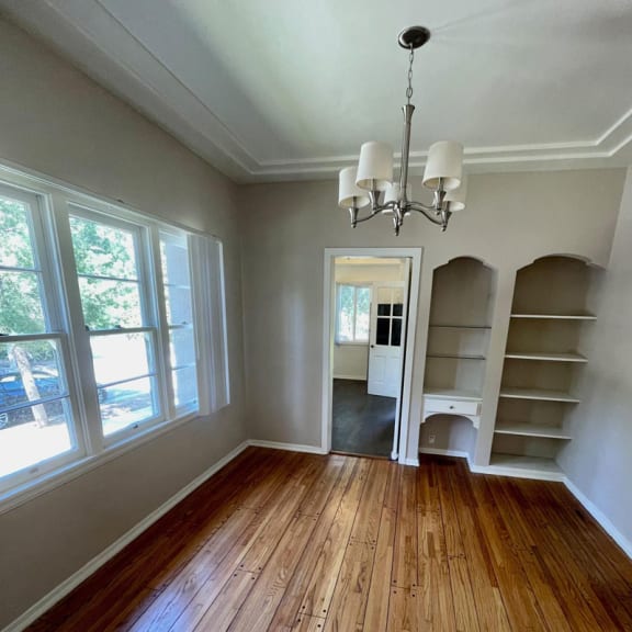 an empty dining room with a chandelier and bookshelves