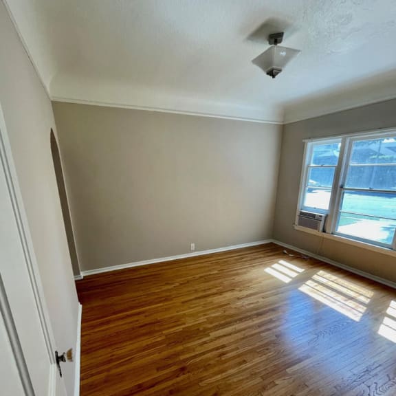 an empty room with hardwood floors and a window