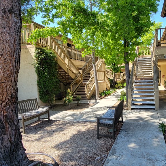 a courtyard with benches and stairs in front of a building