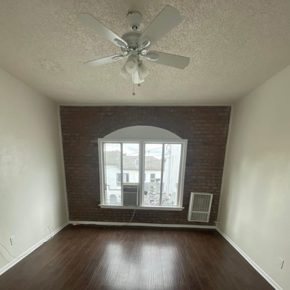 an empty room with a ceiling fan and a window